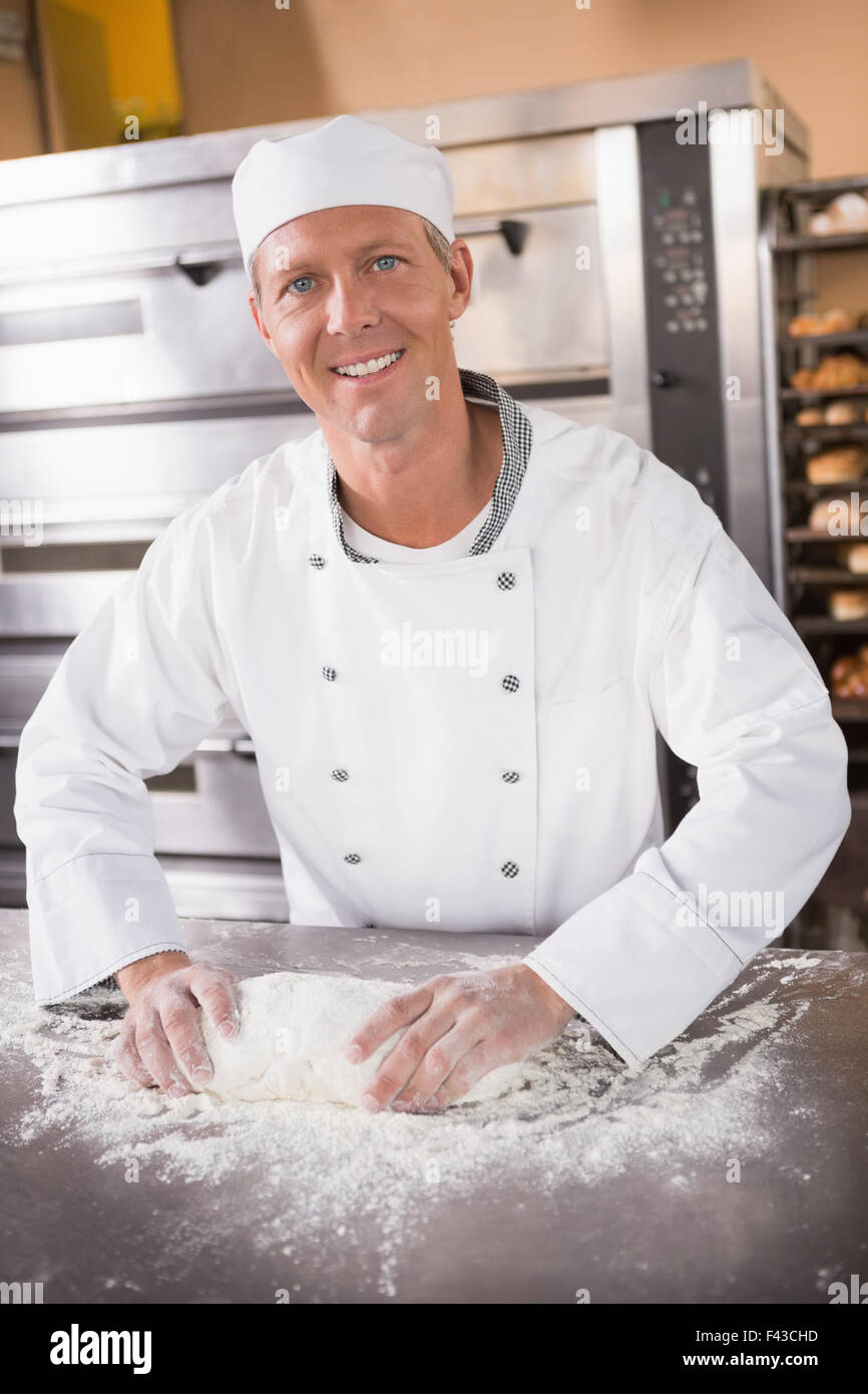 Smiling baker kneading dough on counter Stock Photo Alamy