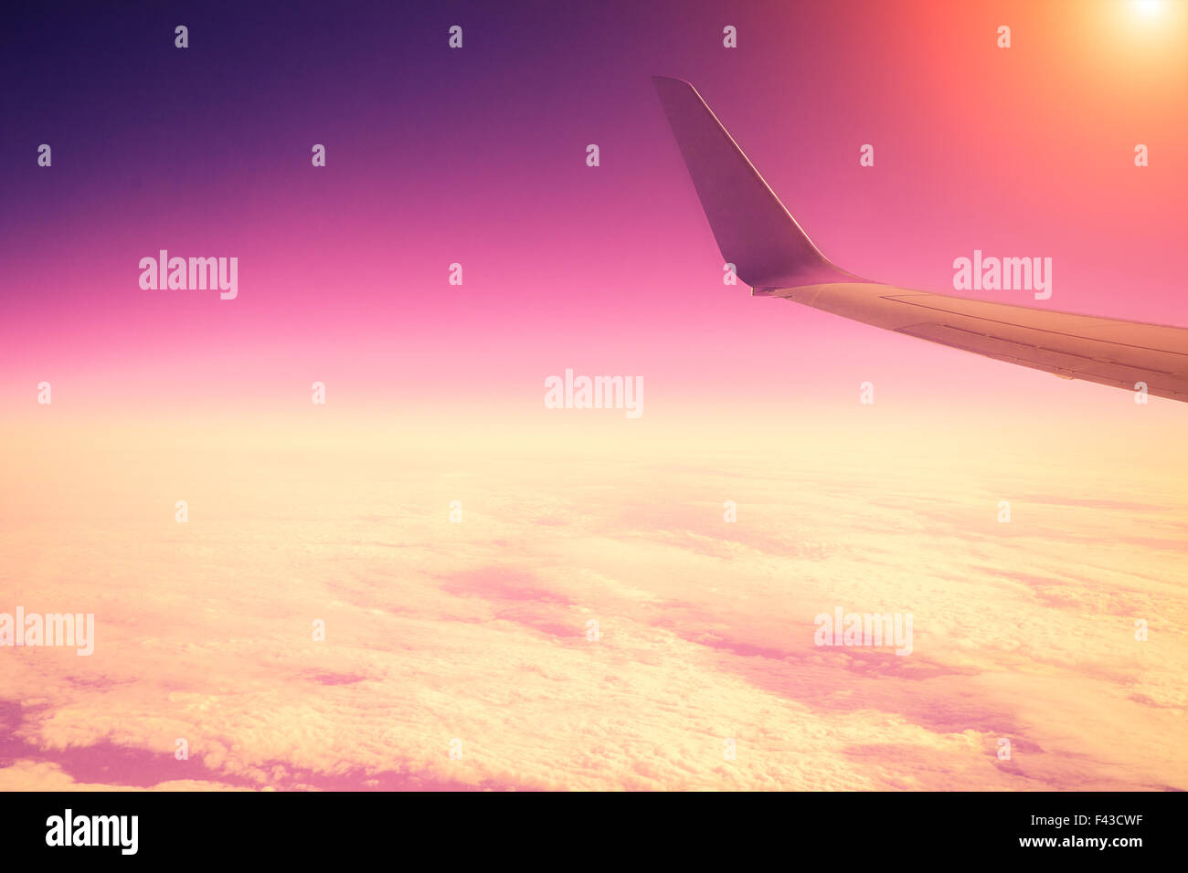 Airplane flying above clouds at pink sunrise Stock Photo - Alamy