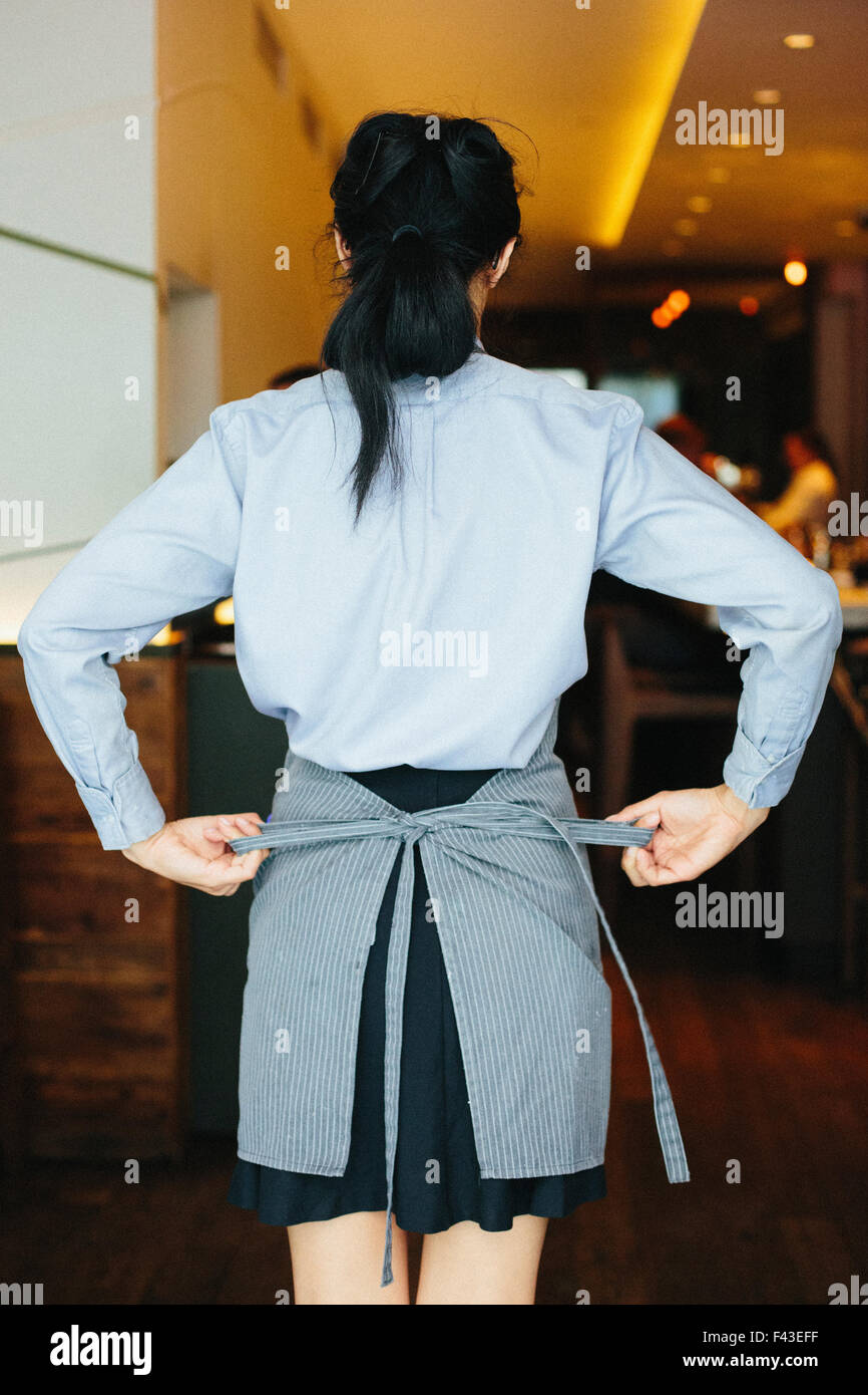 Young waitress tying her apron at a city restaurant Stock Photo Alamy