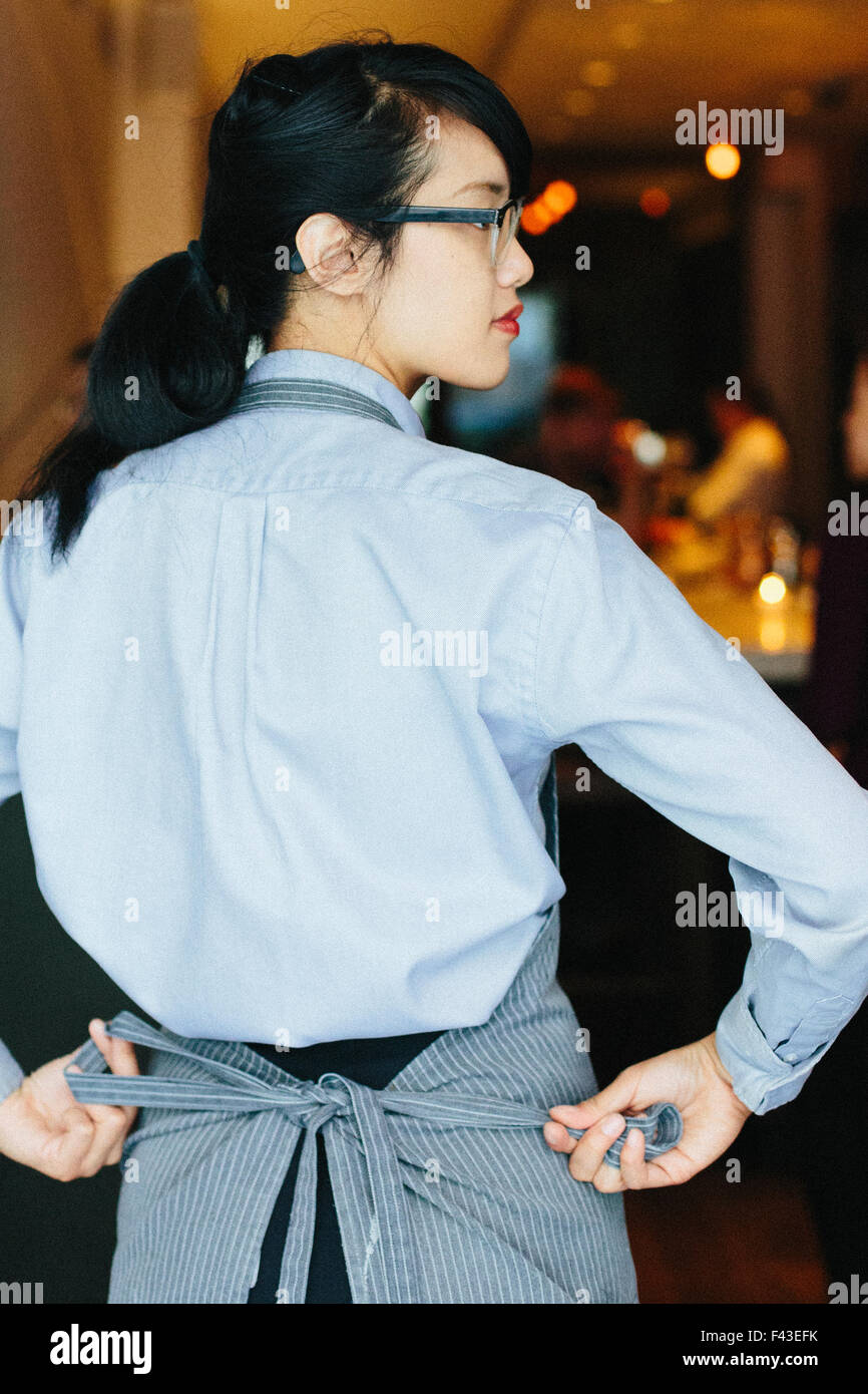 Young waitress tying her apron at a city restaurant Stock Photo Alamy
