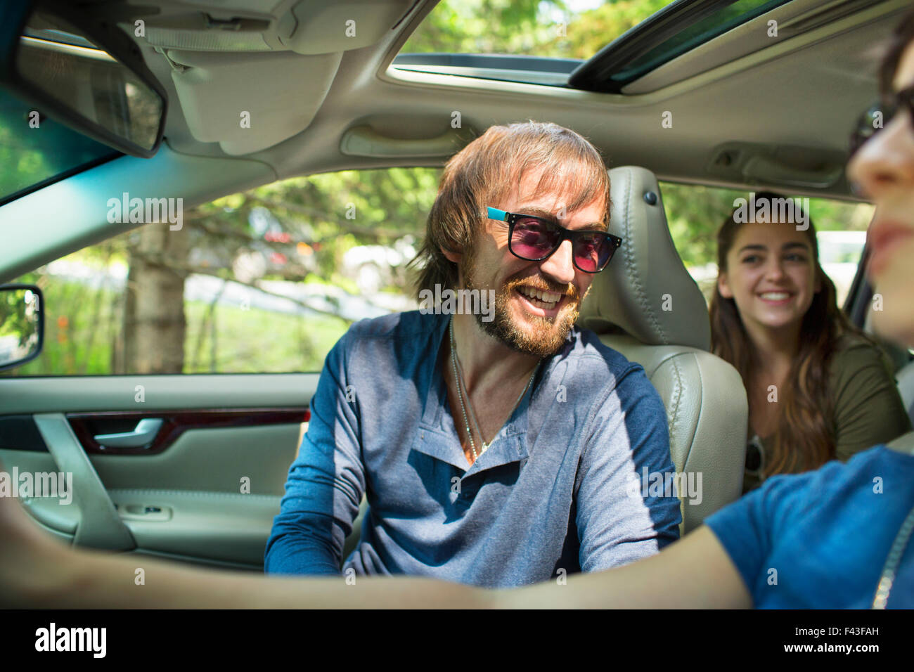 A group of people inside a car, on a road trip. A driver and two ...