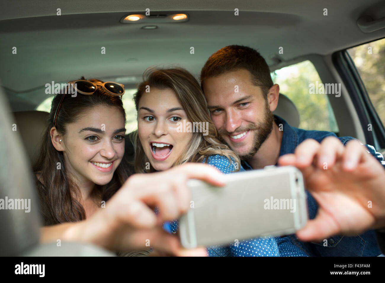 A group of people inside a car, two women and a man taking a selfy. Stock Photo