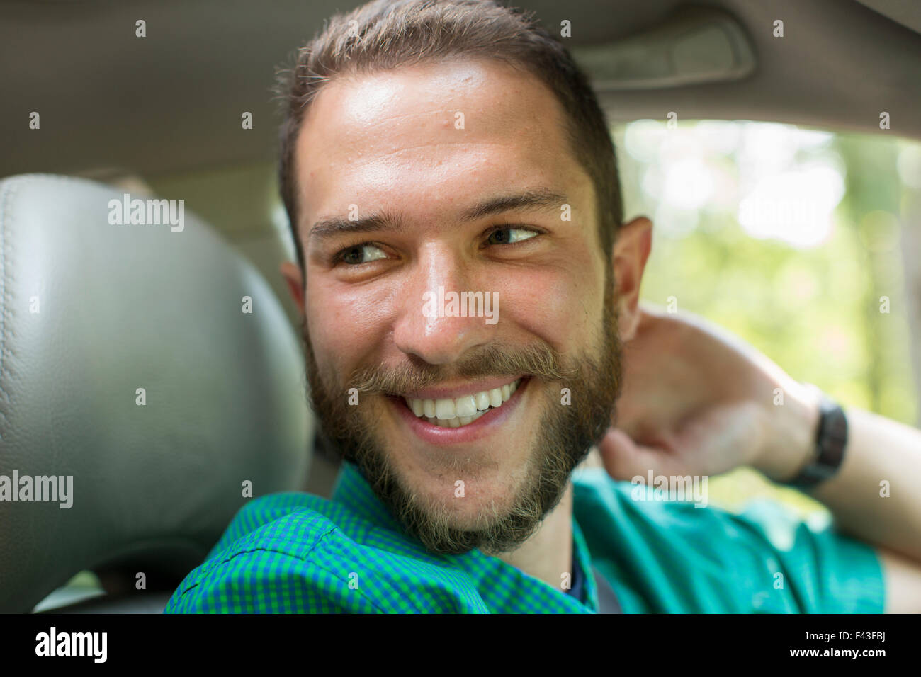 A man sitting in the driving seat of a car looking sideways Stock Photo
