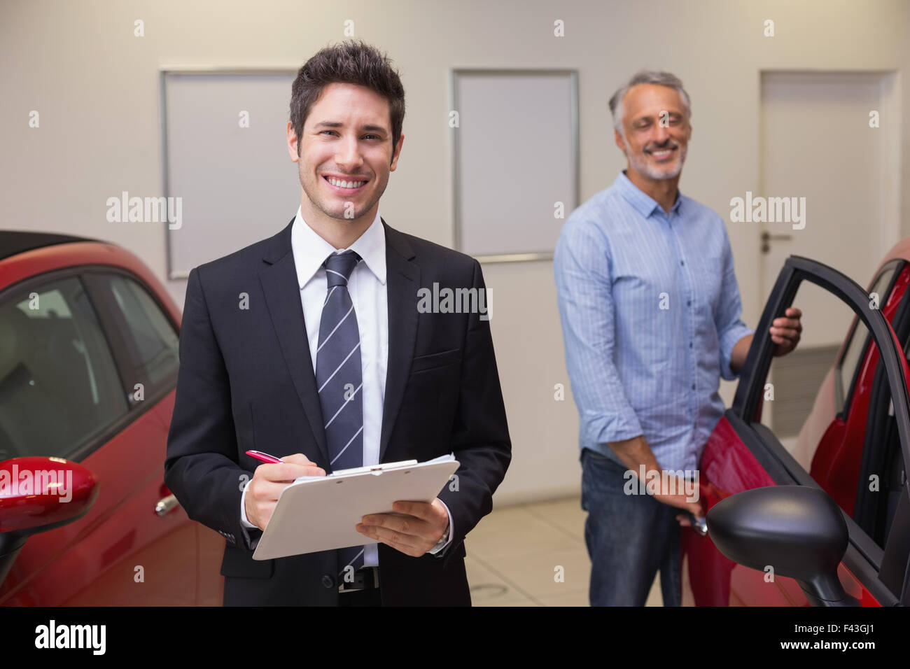Smiling businessman writing on clipboard Stock Photo - Alamy