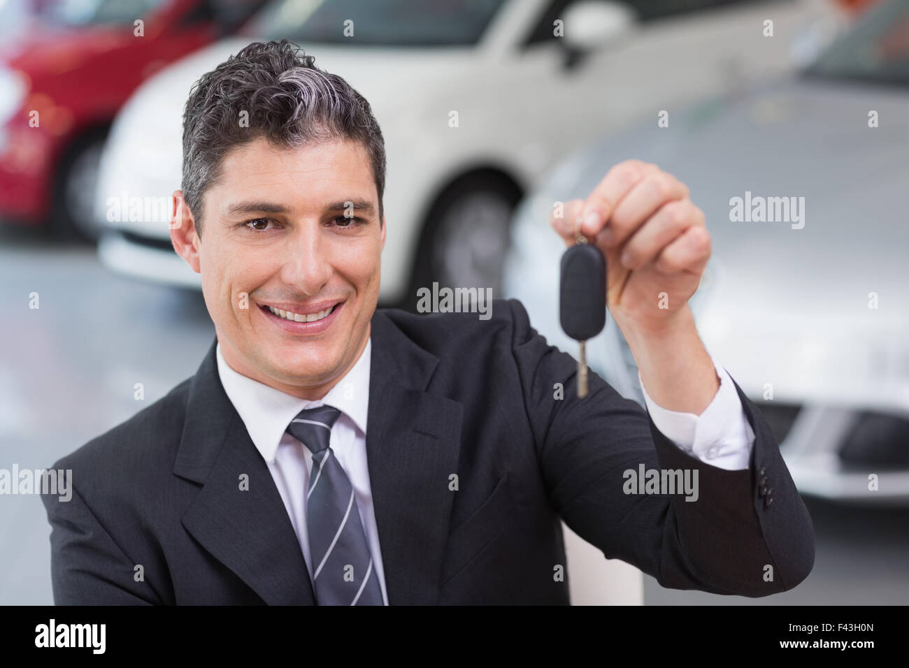 Smiling salesman giving a customer car key Stock Photo - Alamy