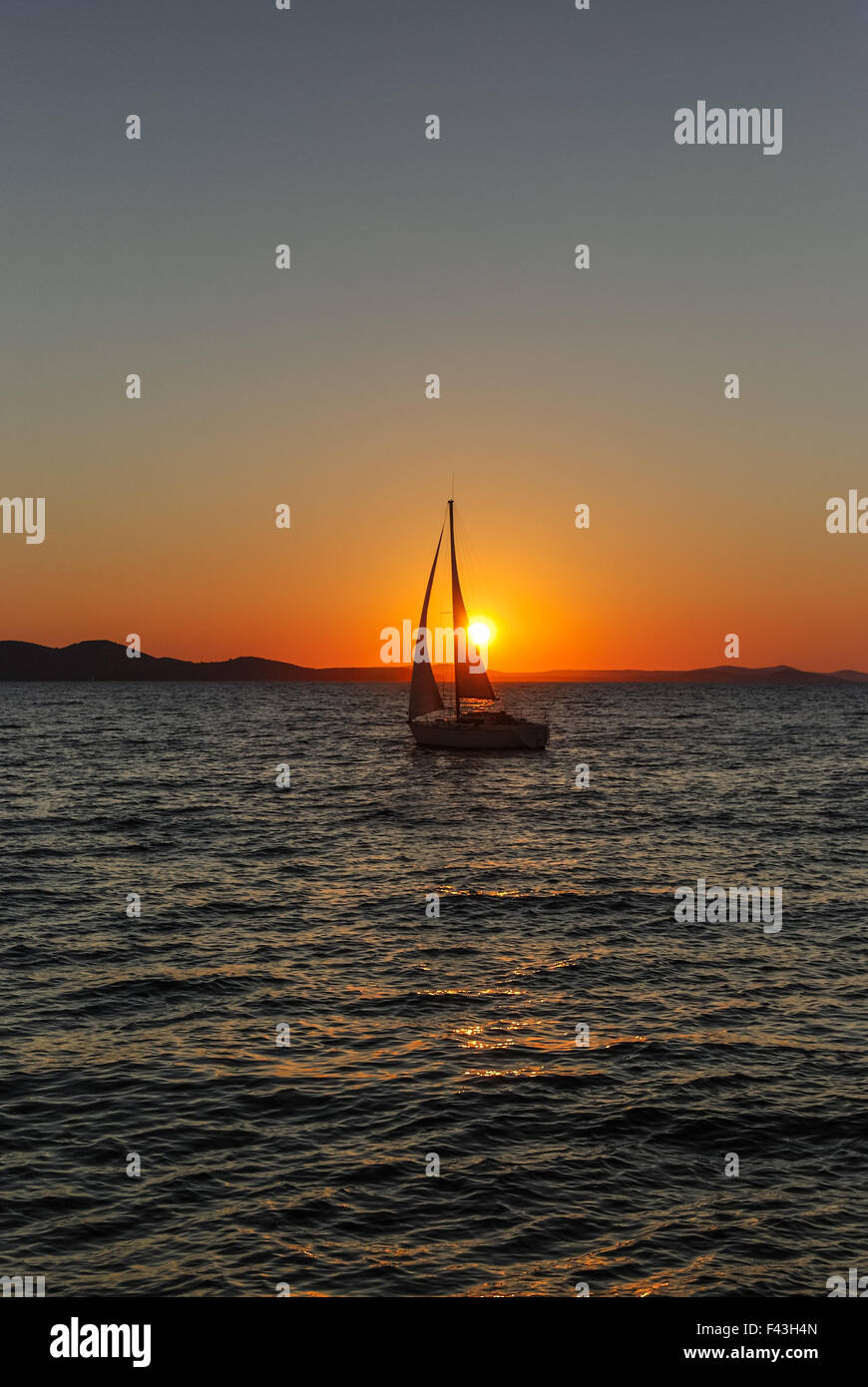 Sailboat at sea in the sunset Stock Photo - Alamy