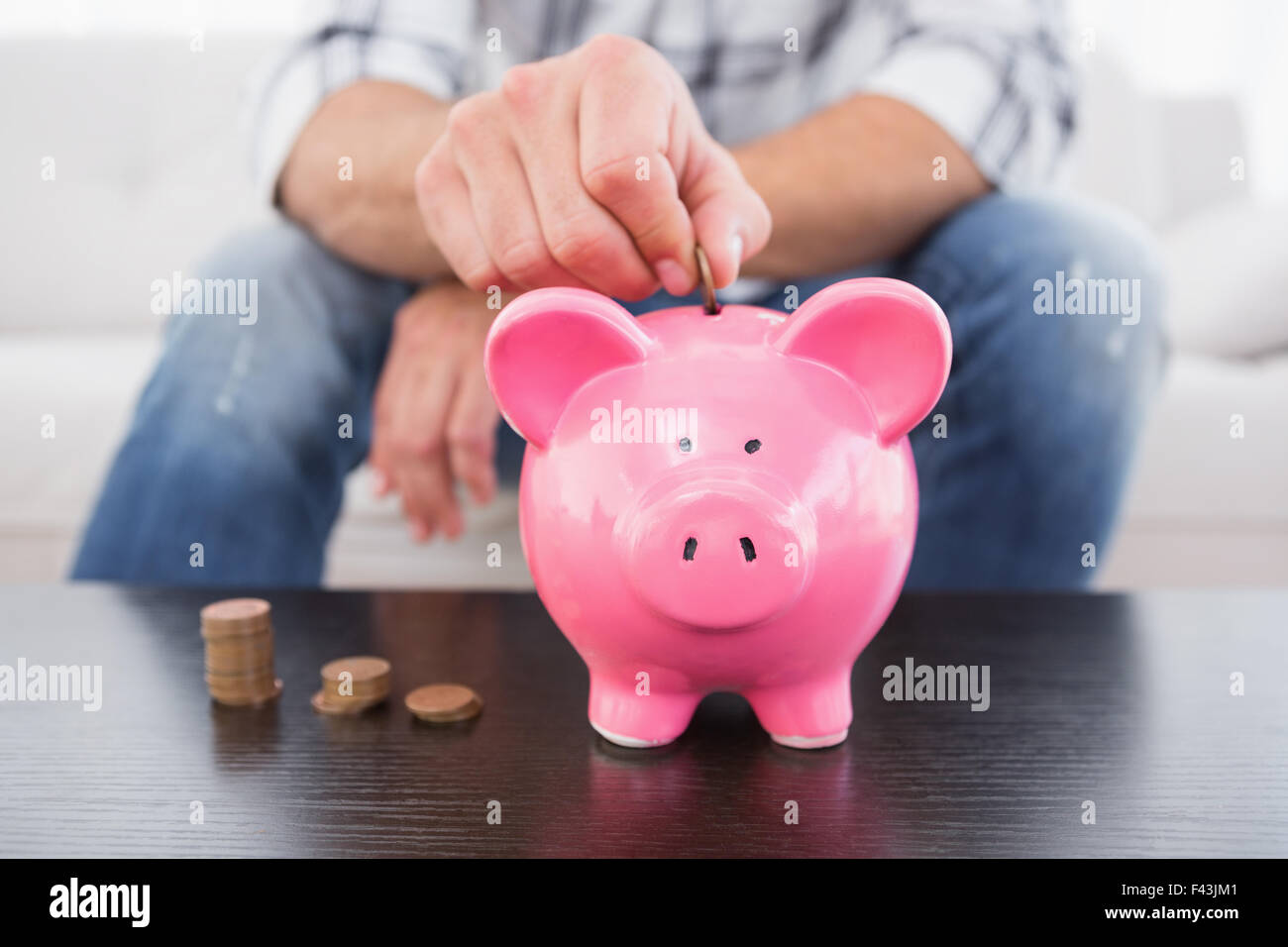 A man putting coins in piggy bank Stock Photo - Alamy