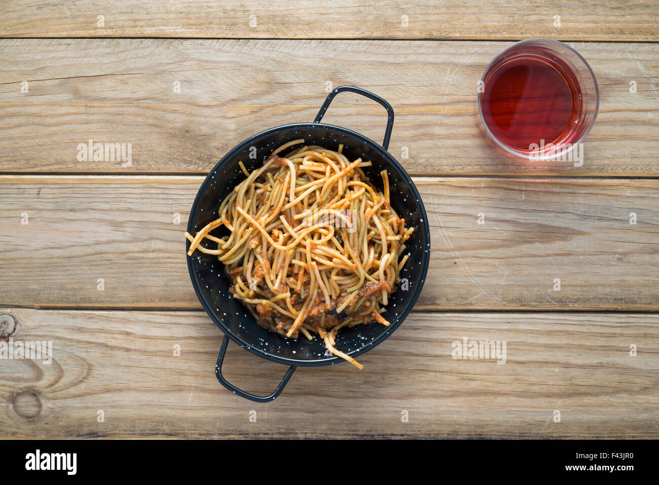 Spaghetti with tomato sauce on wooden table. Not forgetting the glass of claret Stock Photo