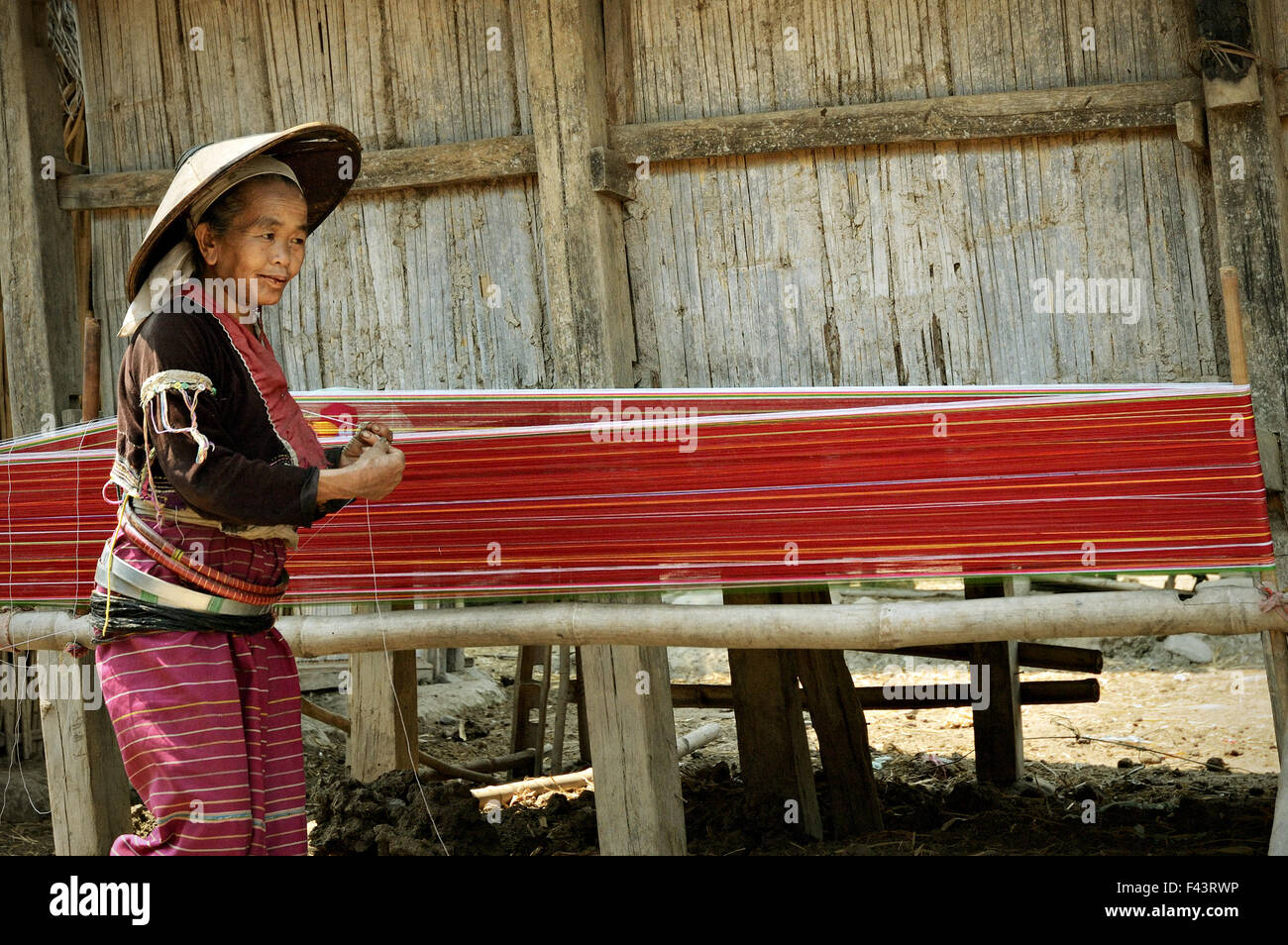 Old Palaung woman with a conical hat weaving outside in a village around Kengtung (Kyaingtong), Shan State, Myanmar Stock Photo