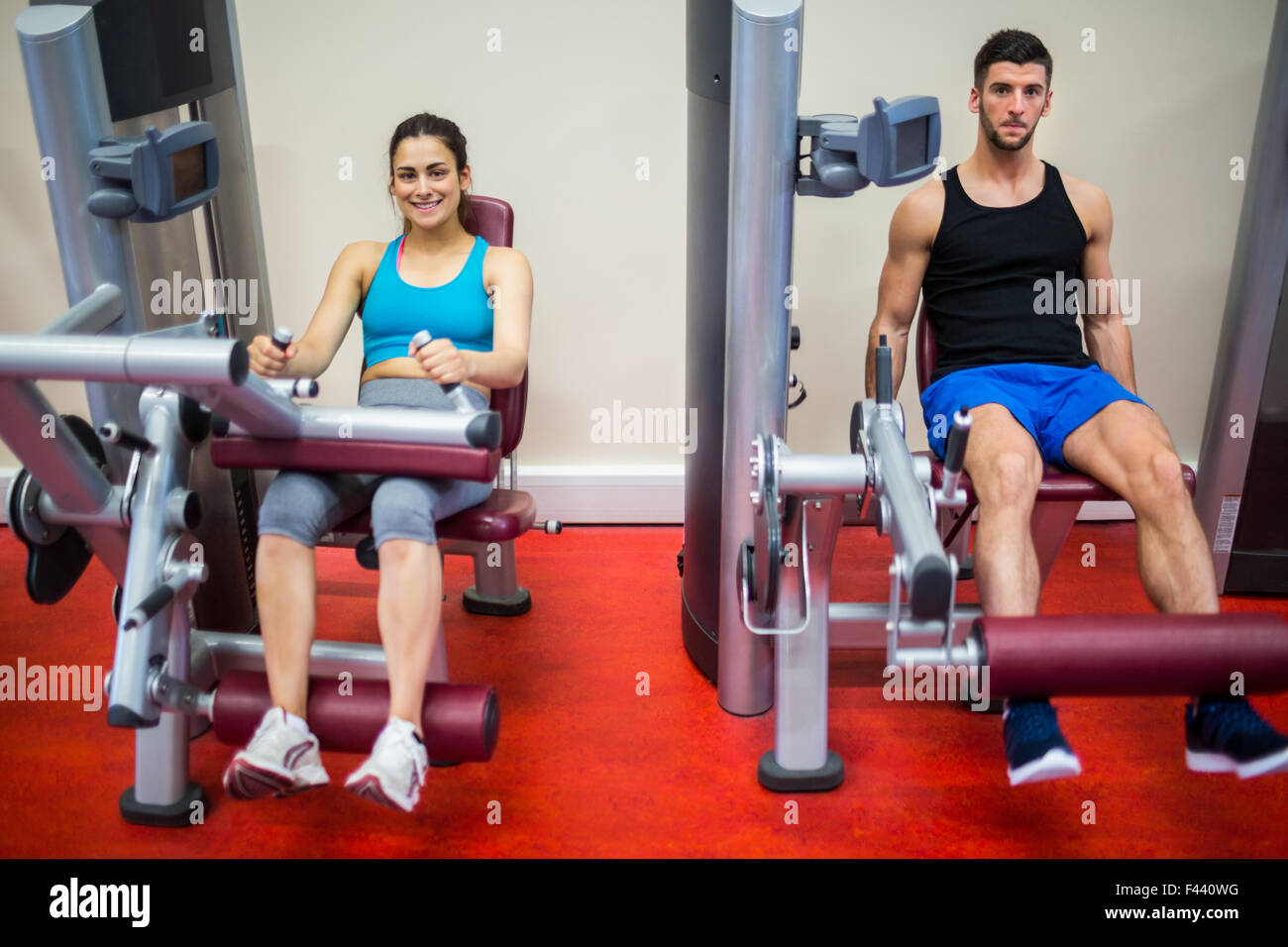 Man and woman both using weights machine Stock Photo - Alamy