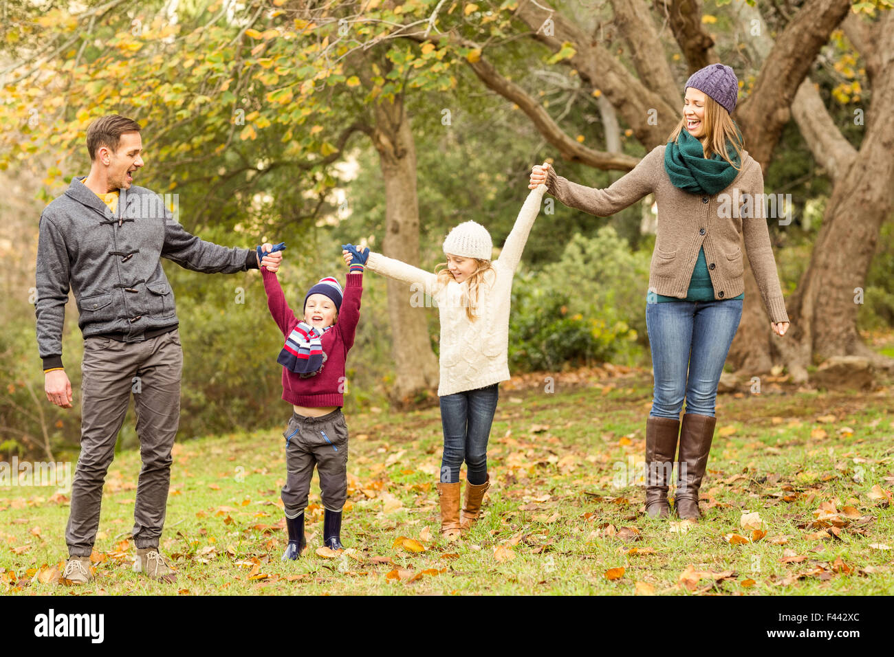Smiling young family raising their hands Stock Photo