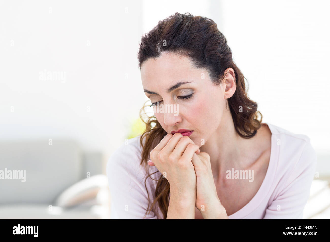 Sad brunette sitting on the couch Stock Photo