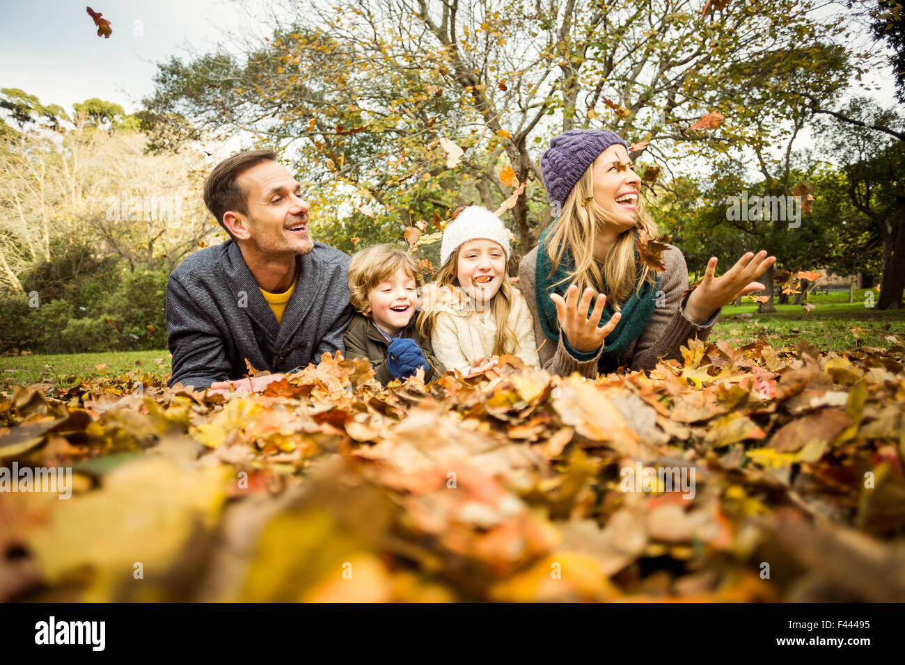 Smiling young family throwing leaves around Stock Photo