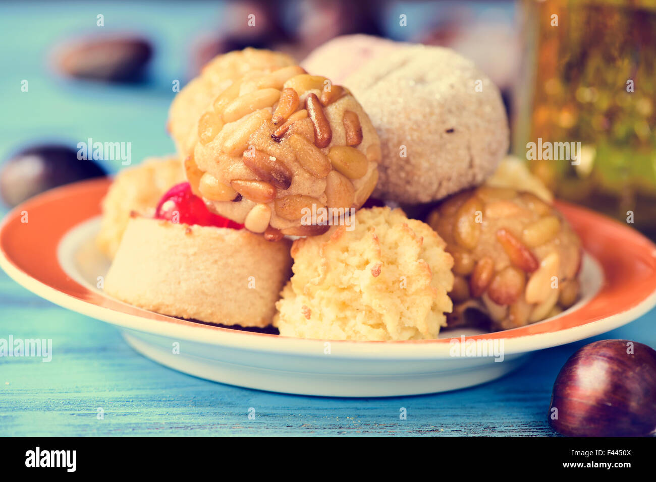 a plate with some different panellets, typical pastries of Catalonia, Spain, eaten in All Saints Day, and some chestnuts on a bl Stock Photo