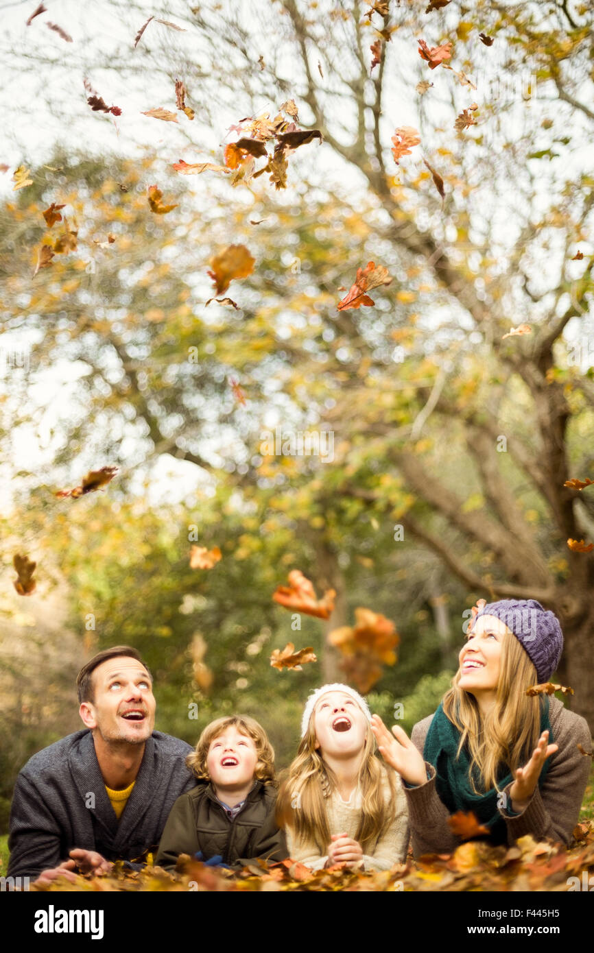 Smiling young family throwing leaves around Stock Photo