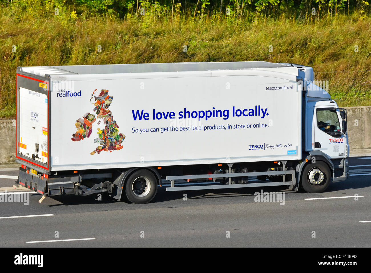 Tesco supply chain lorry used for smaller local supermarket store delivery with uk map & advertising driving along English motorway Stock Photo