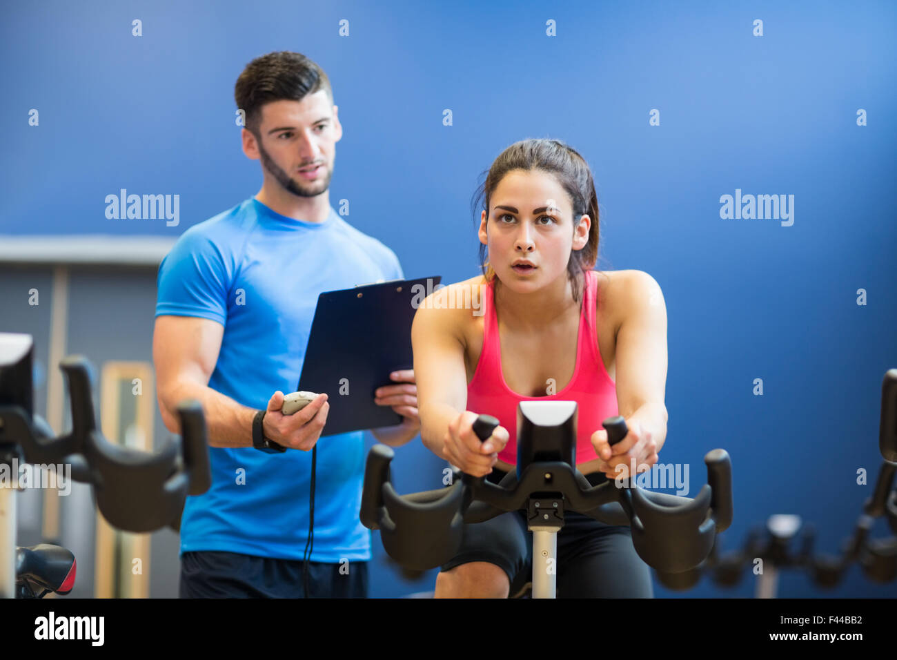 Woman on exercise bike with trainer timing her Stock Photo