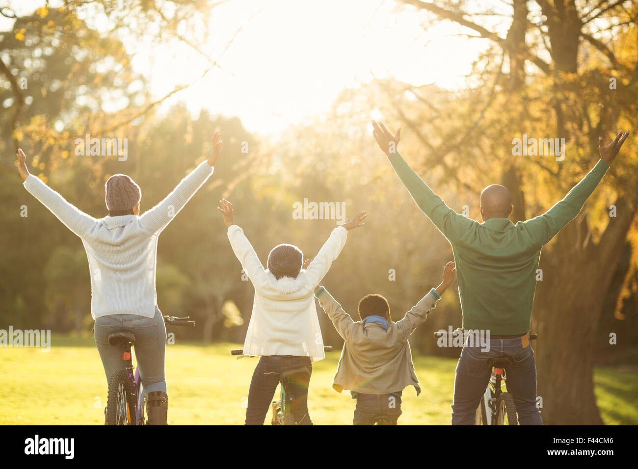 Rear view of a young family with arms raised on bike Stock Photo