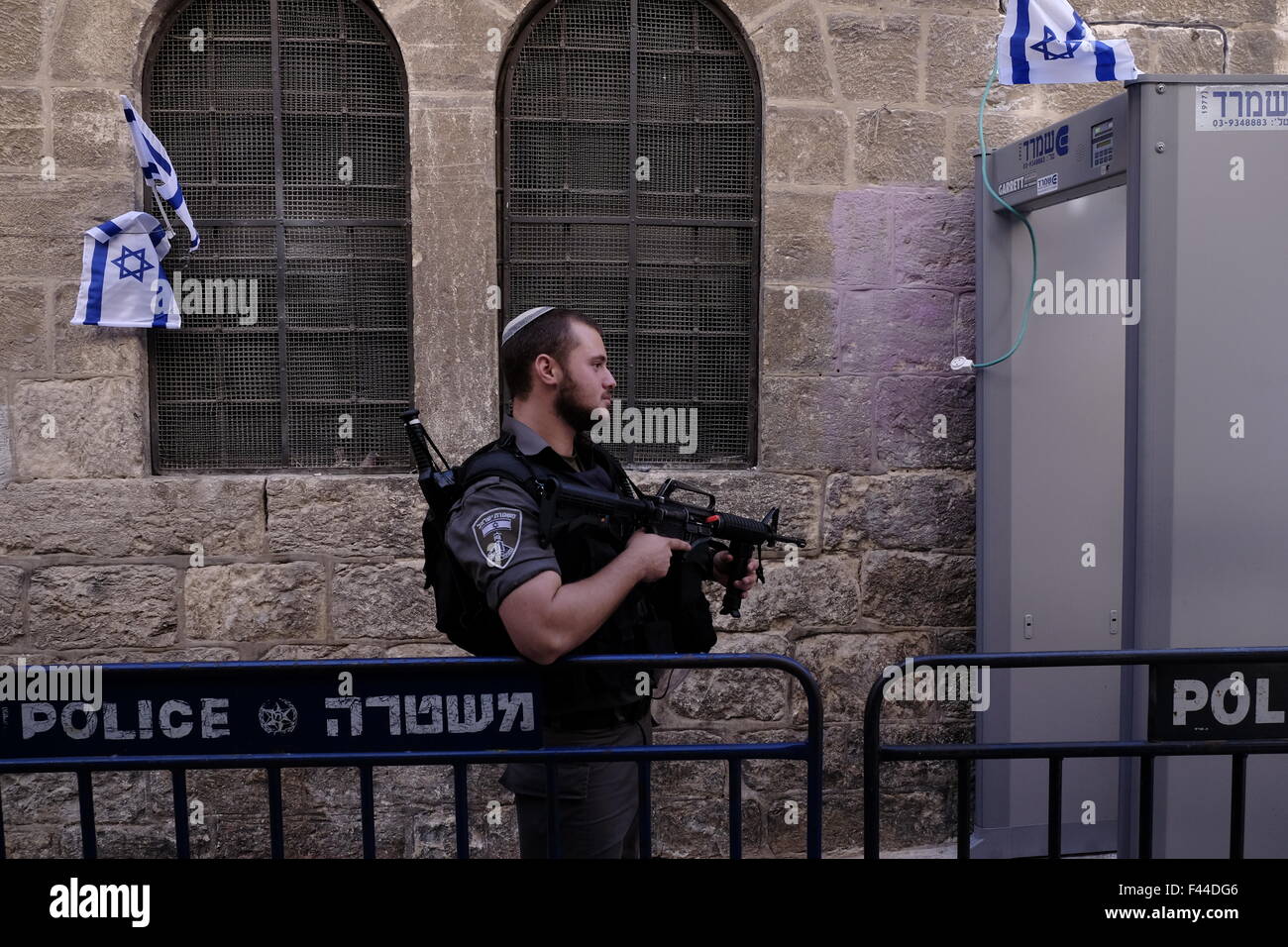 Jerusalem, Israel. 14th October, 2015. An armed Israeli border policeman stands guard next to a metal detector being installed in the Muslim Quarter in Jerusalem's Old City, following a wave of terror attacks. East Jerusalem, Israel on 14 October 2015  Israel has been the scene of several stabbing attacks over the last few weeks, leaving dozens of people injured and resulting in several deaths on both sides. Many fear that the uprisings will lead to a full scale conflict between Israel and Palestine. Credit:  Eddie Gerald/Alamy Live News Stock Photo