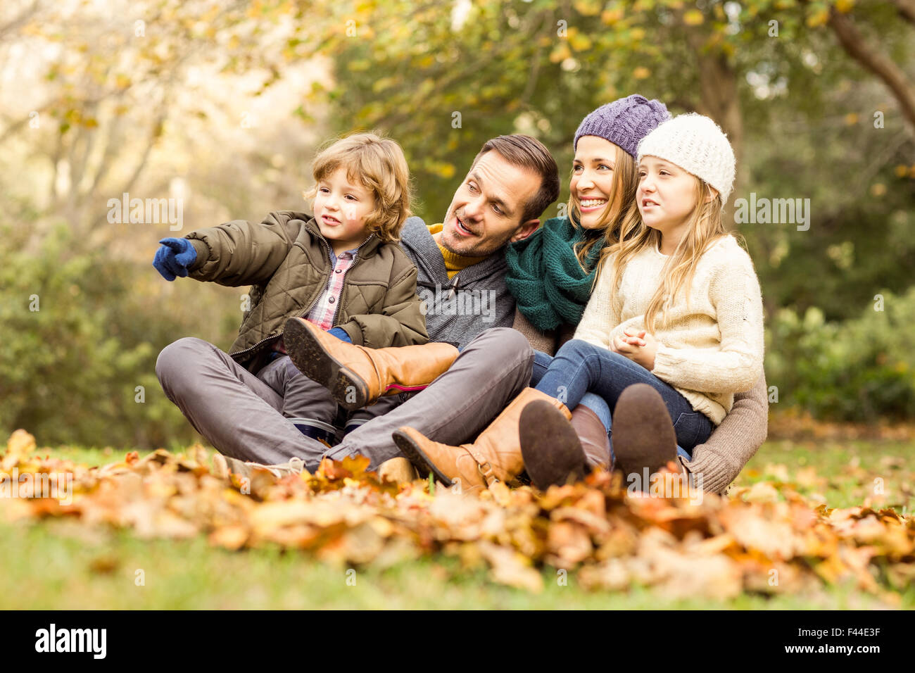 Smiling young family sitting in leaves Stock Photo