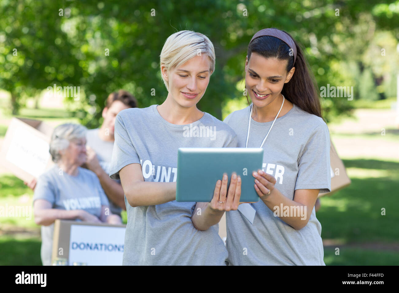 Happy volunteer friends using tablet pc Stock Photo