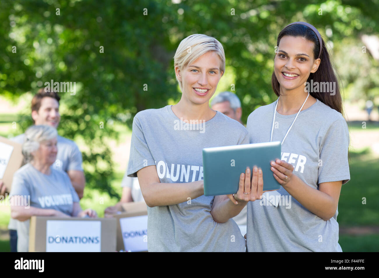 Happy volunteer friends using tablet pc Stock Photo