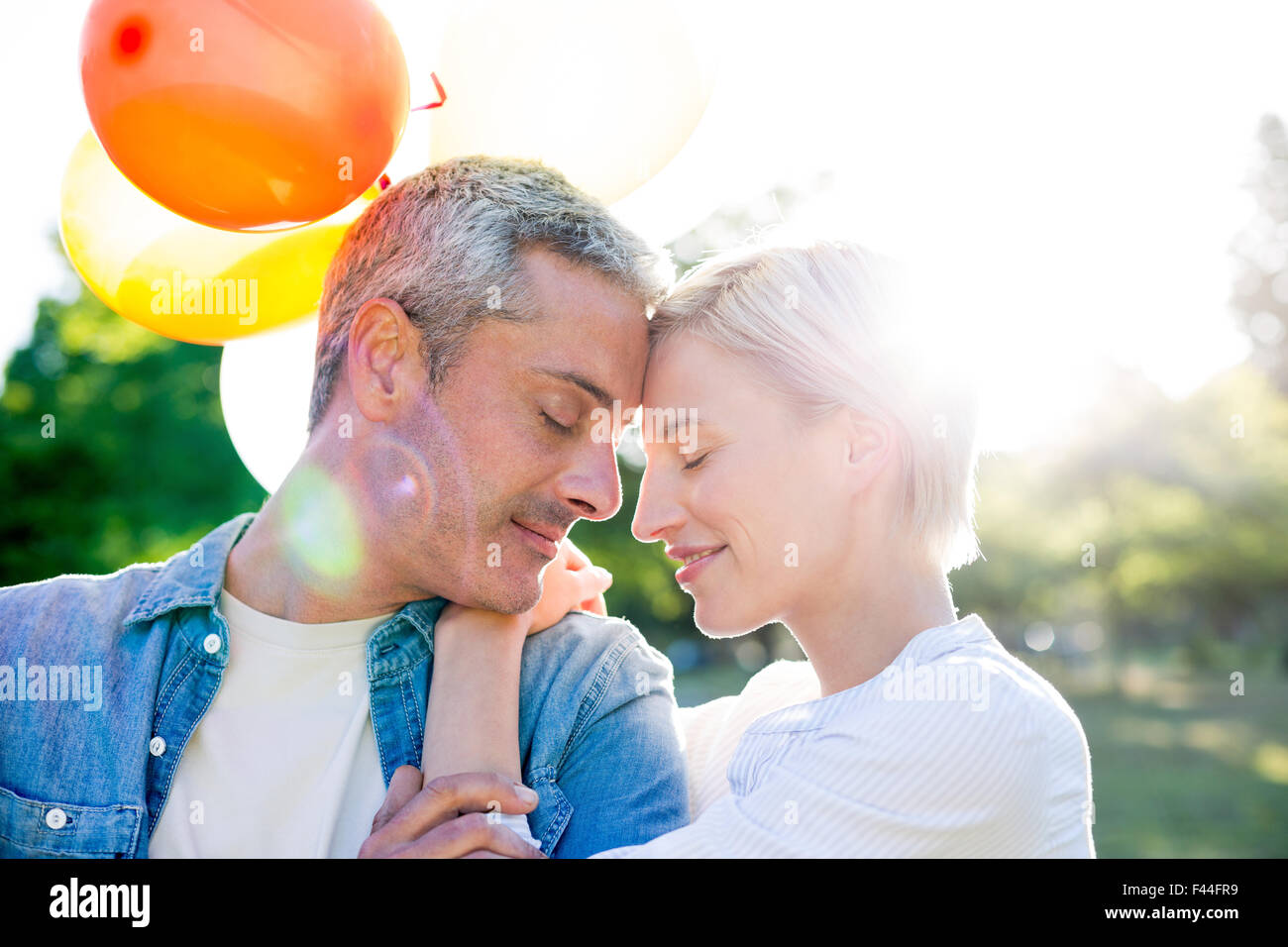 Cute couple holding balloons at the park Stock Photo - Alamy