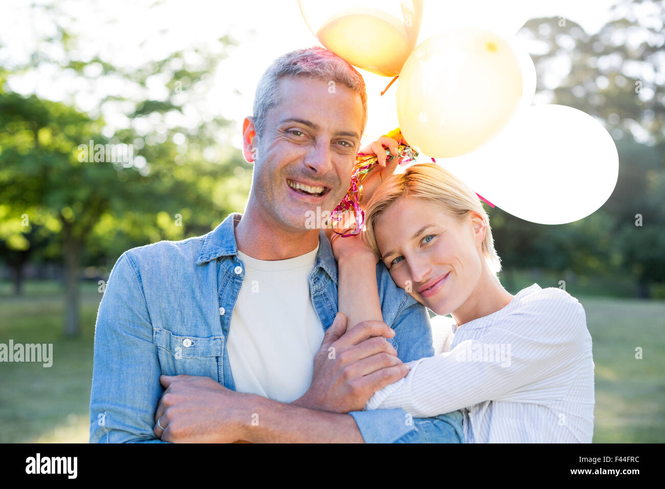 Happy couple holding balloons at the park Stock Photo - Alamy