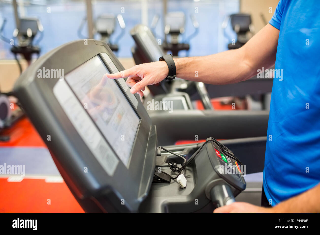 Man adjusting the settings of a treadmill Stock Photo