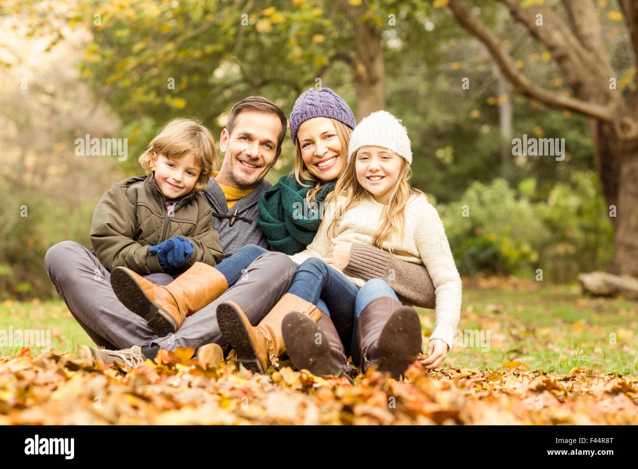 Smiling young family sitting in leaves Stock Photo