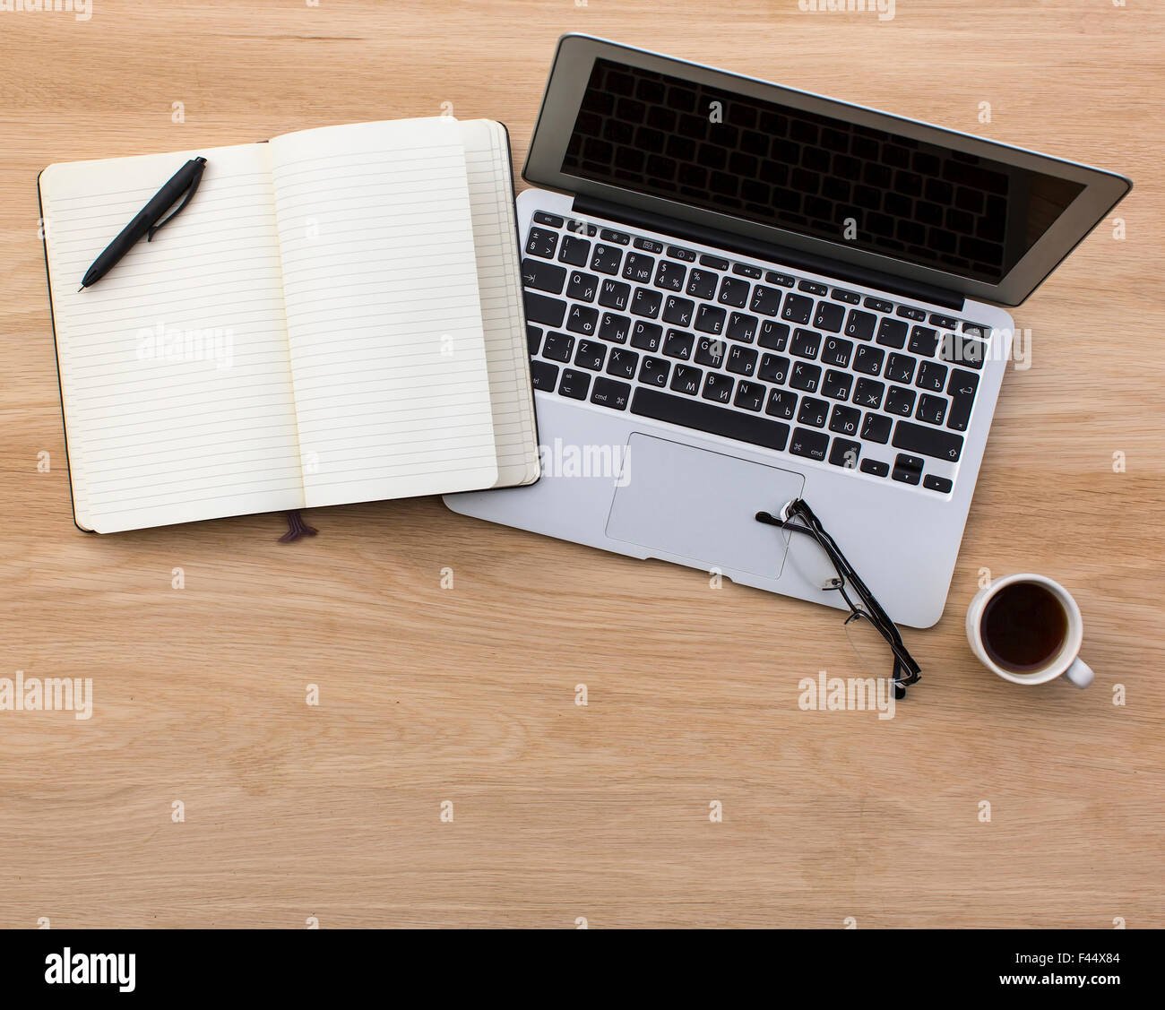 Laptop and opened Notepad on wooden table top view. Stock Photo