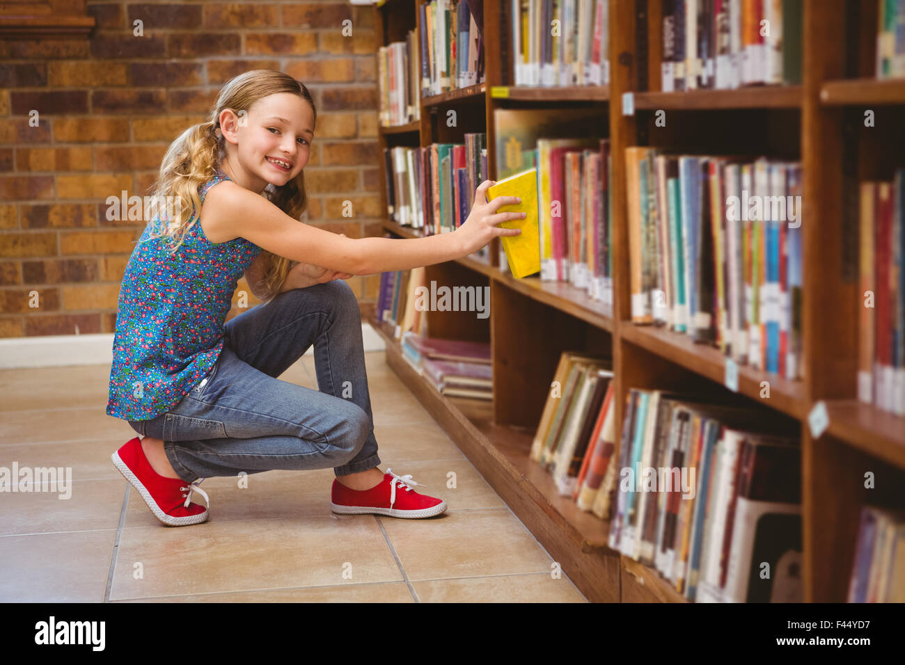 Cute little girl selecting book in library Stock Photo - Alamy
