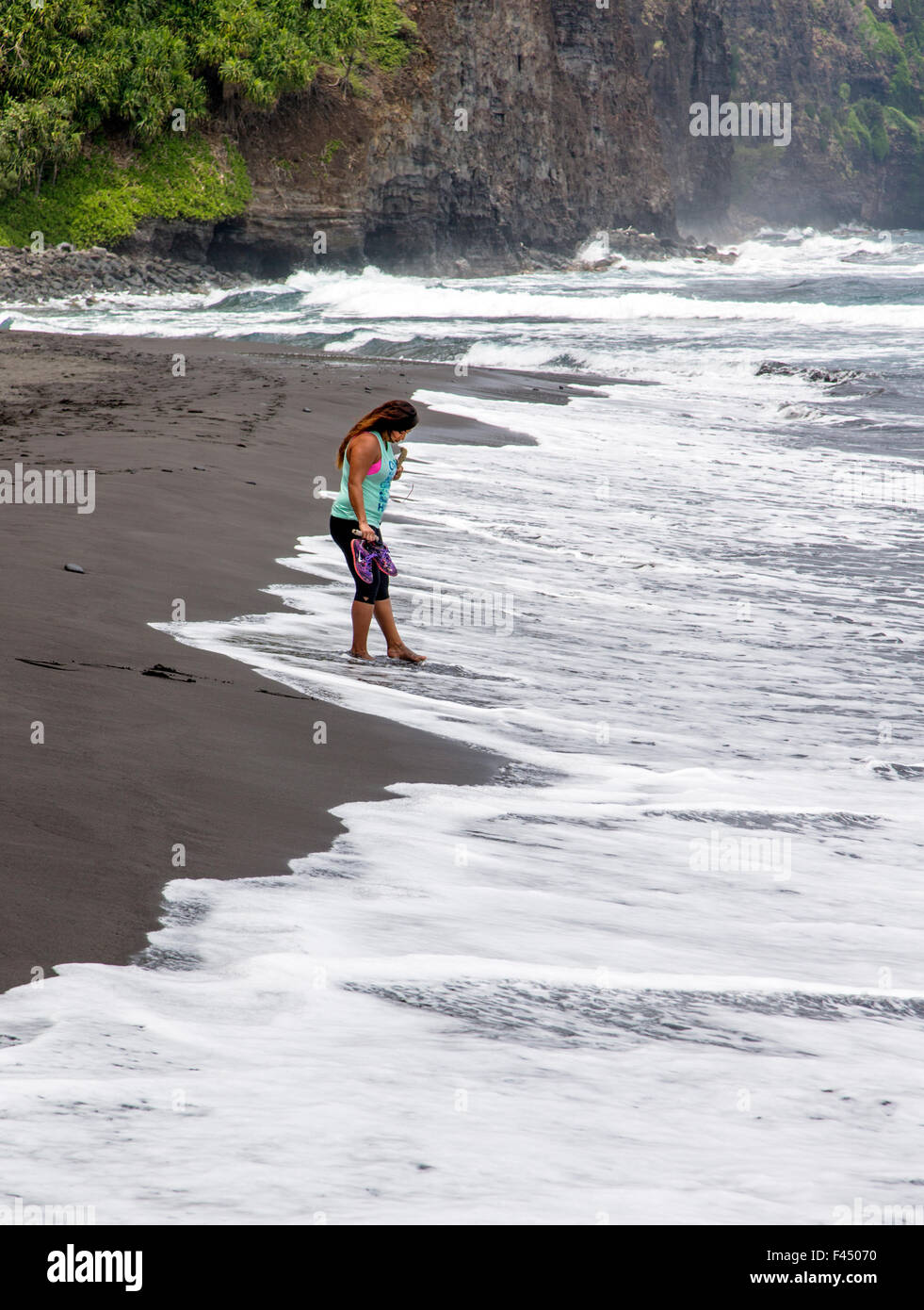 Native Hawaiian woman on beach at Akoakoa Point, Polulu Valley, Big Island of Hawai’i, Hawai’i, USA Stock Photo