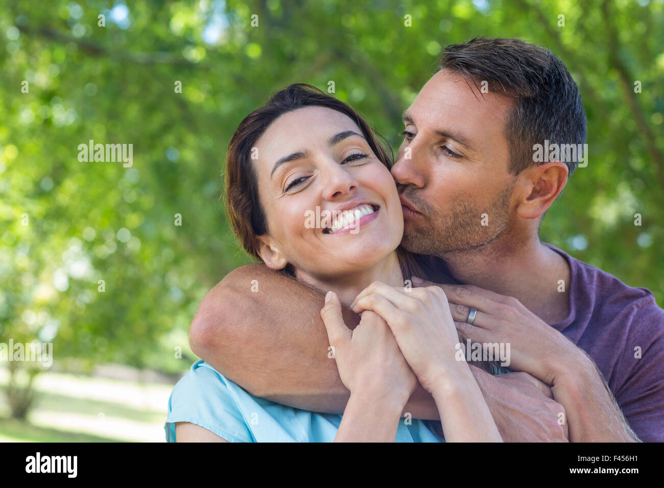 Happy couple smiling at camera in park Stock Photo - Alamy