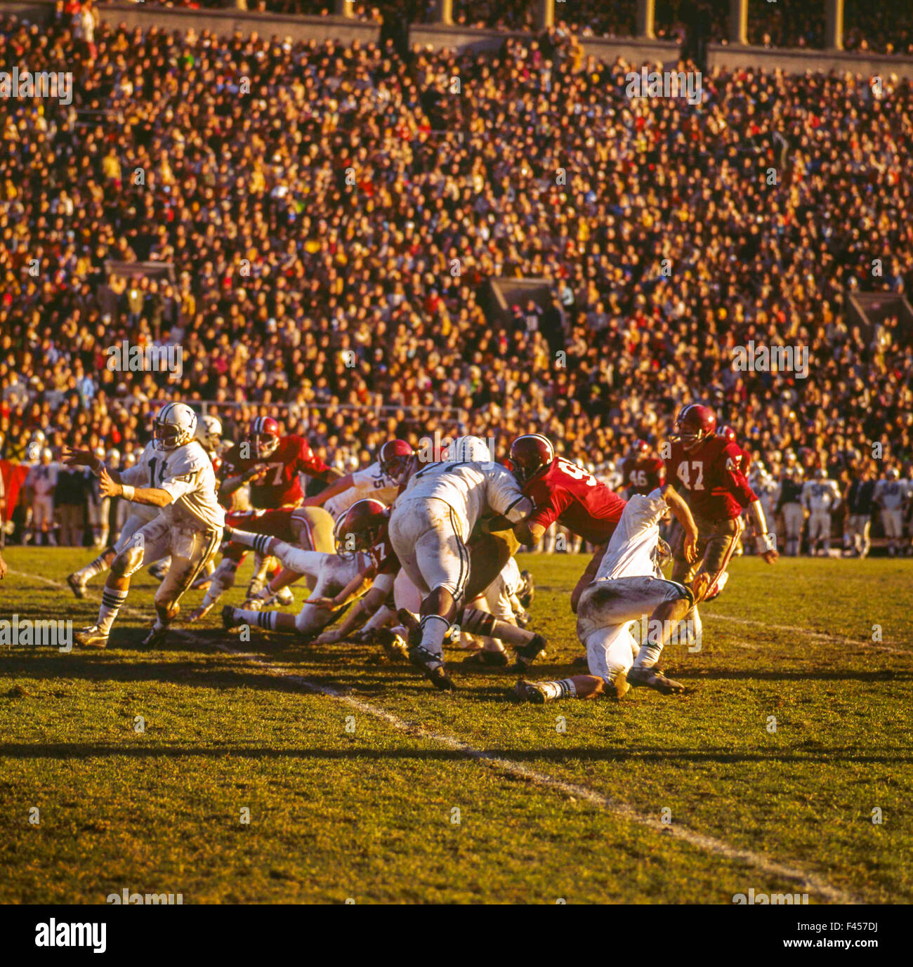Uniformed players play tackle at a Harvard University football game