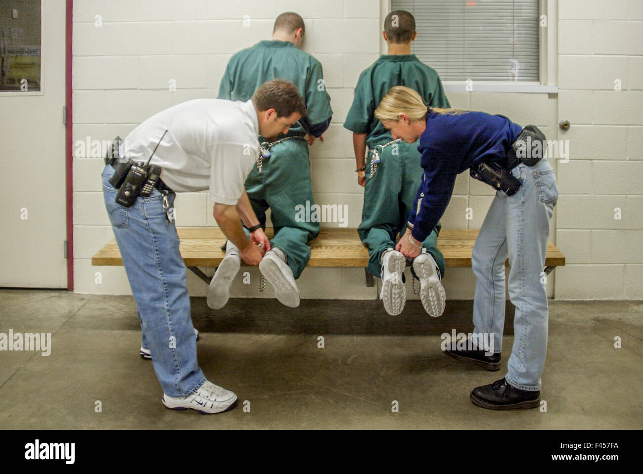 Male and female corrections officers place leg irons on two teenage inmates of an Orange, CA, juvenile prison. Stock Photo