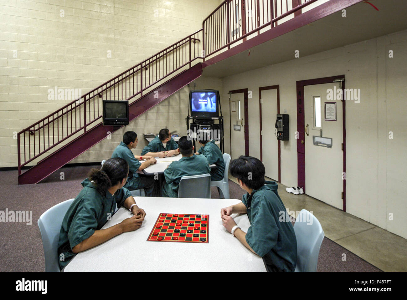 Uniformed Hispanic teenage inmates of an Orange, CA, juvenile prison play checkers in their day room. Note television. Stock Photo