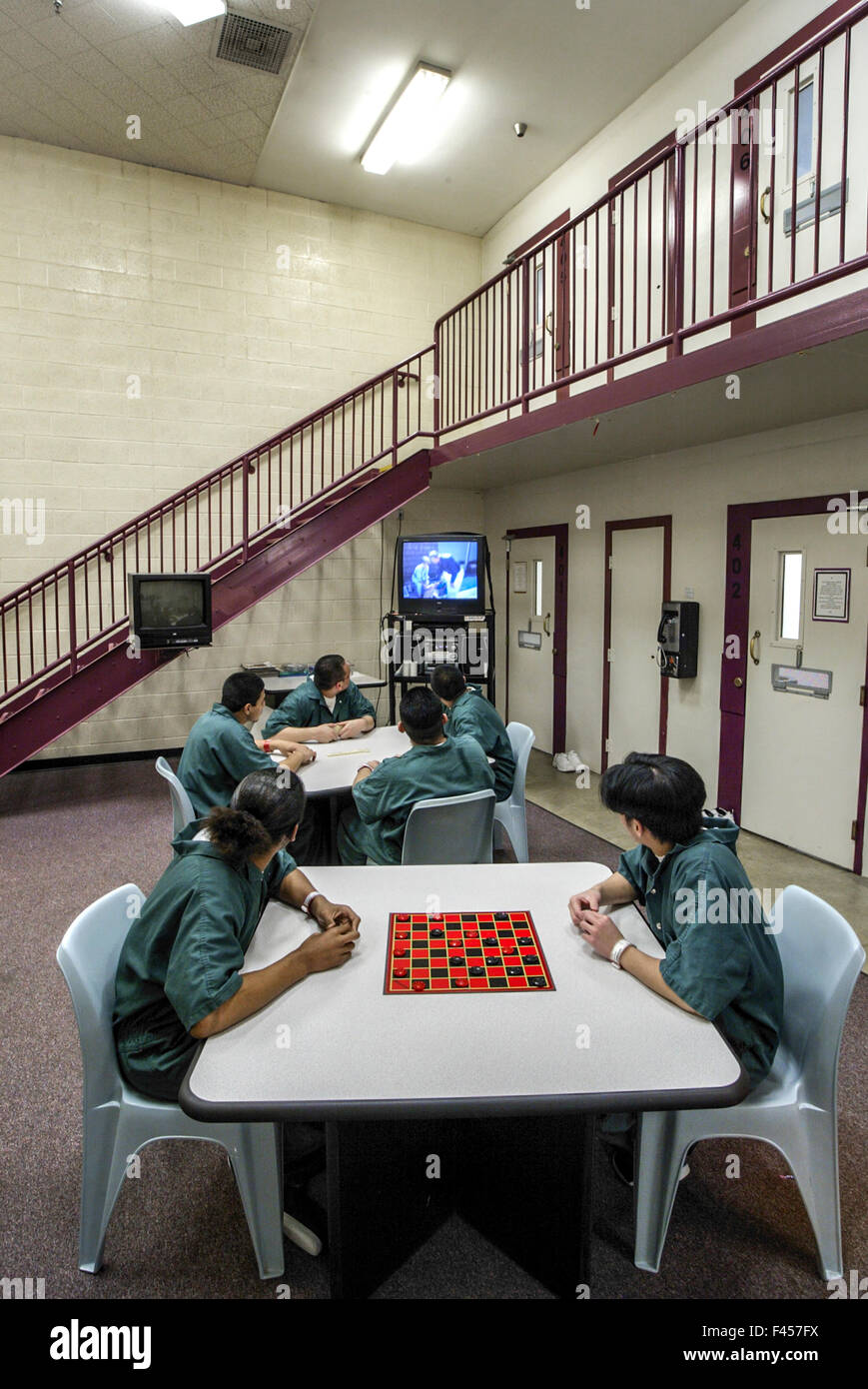 Uniformed Hispanic teenage inmates of an Orange, CA, juvenile prison play checkers in their day room. Note television. Stock Photo