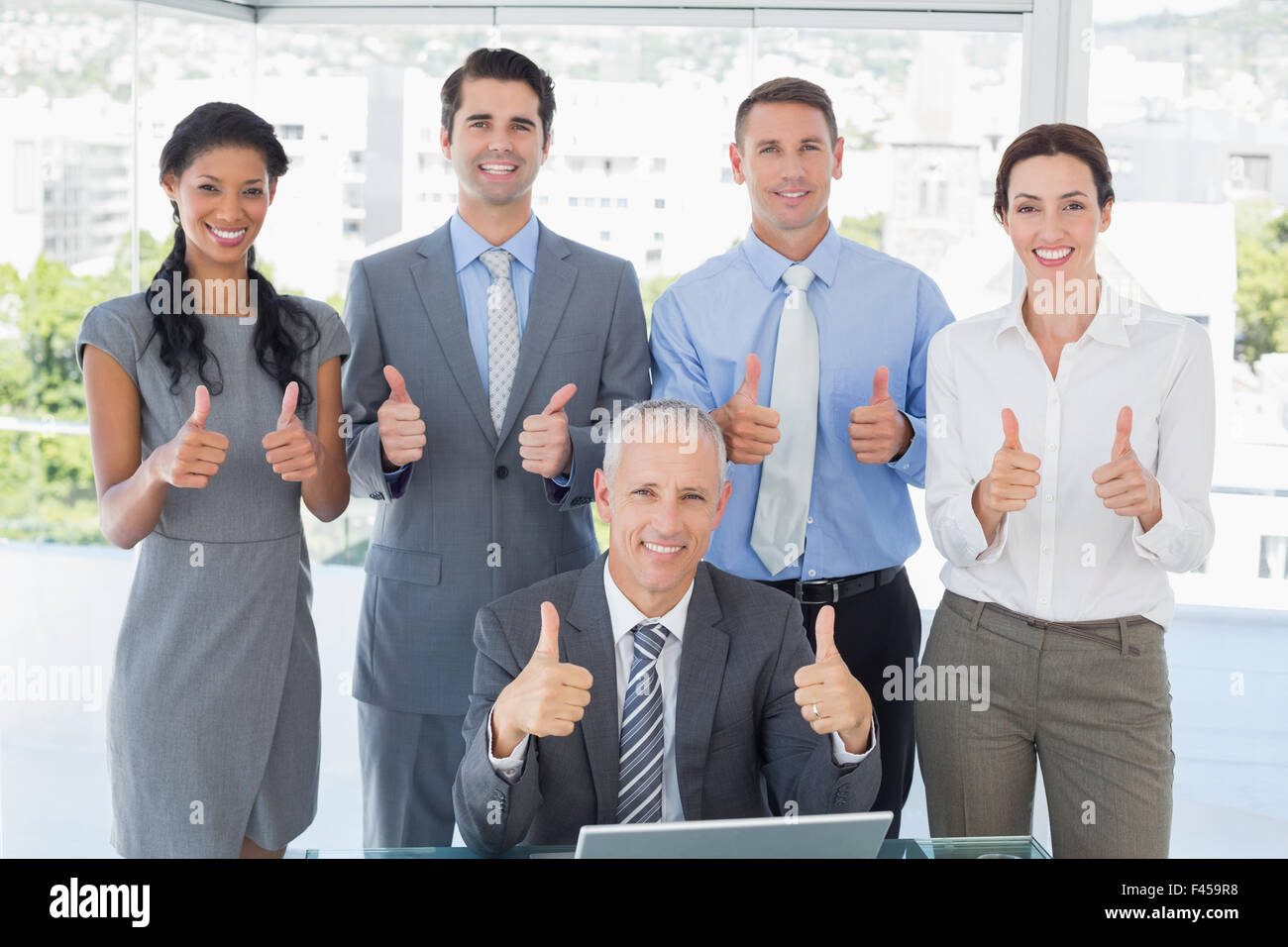 Smiling business team standing thumbs up Stock Photo - Alamy