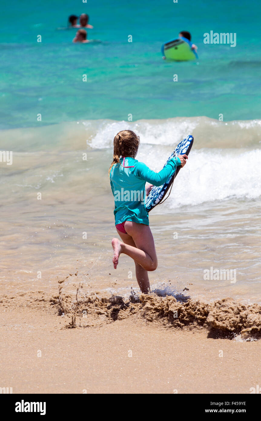 Young girl running to surf the waves, Hapuna Beach, Kohala Coast, Hawai'i, USA Stock Photo