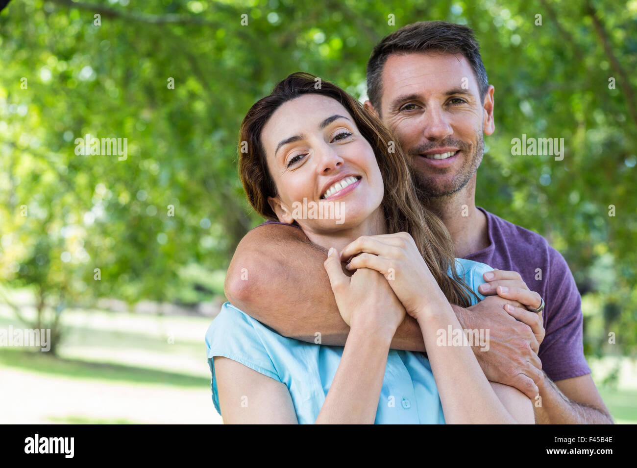 Happy couple smiling at camera in park Stock Photo - Alamy