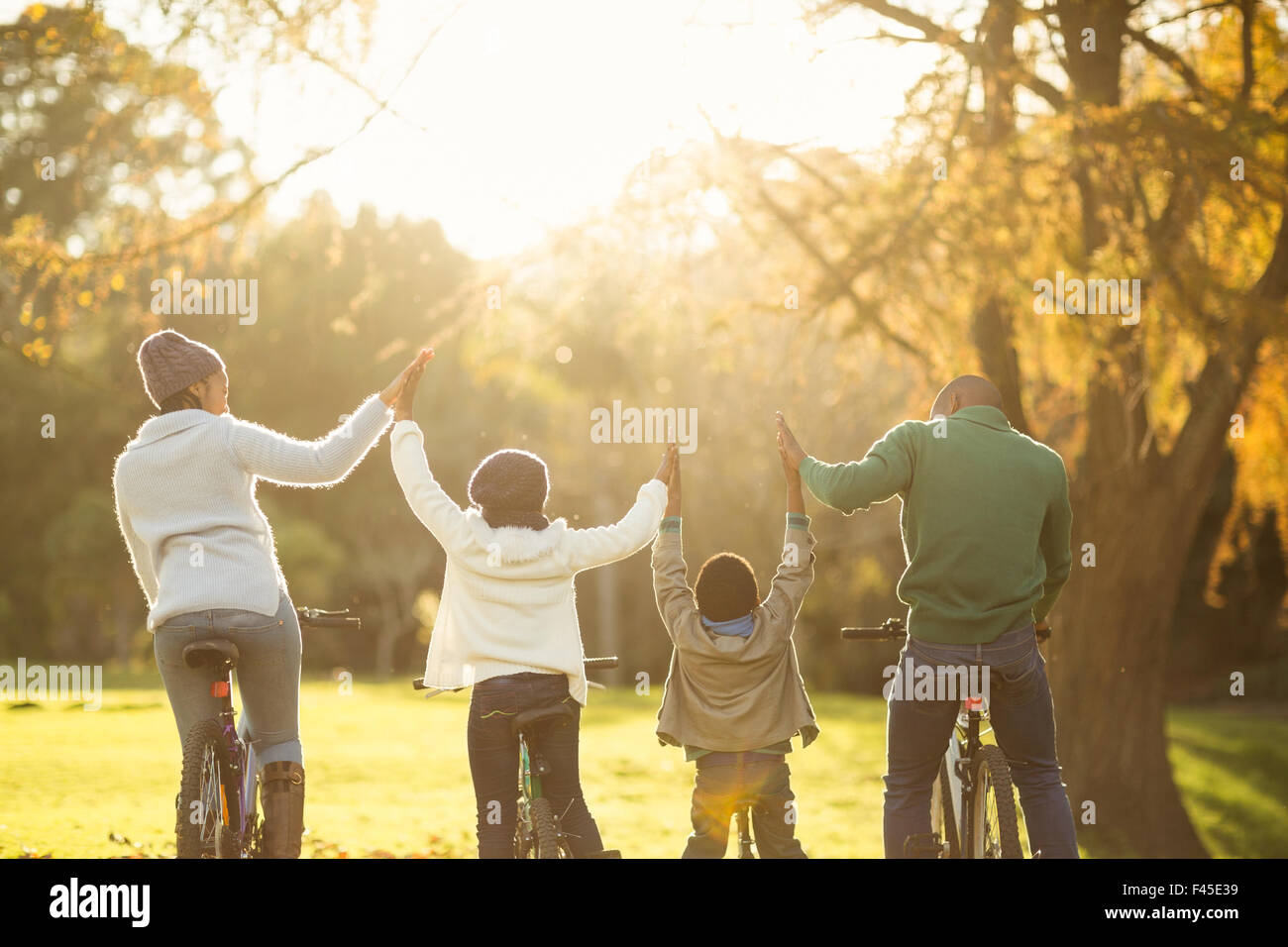 Rear view of a young family with arms raised on bike Stock Photo