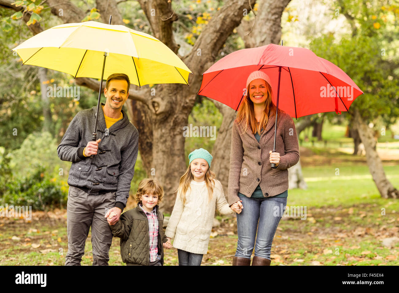 Smiling young family under umbrella Stock Photo