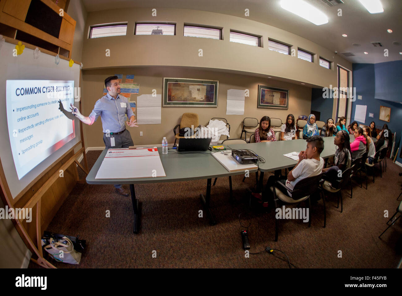 A Hispanic Internet lecturer explains the dangers of cyberbullying to a multiracial teen audience on a careers day at an Anaheim, CA, community center. Stock Photo