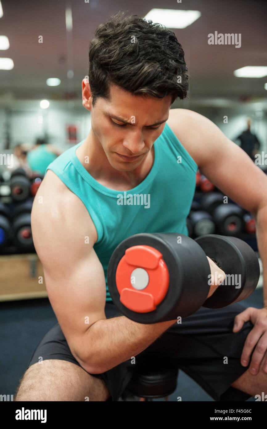 Man lifting dumbbell weight while sitting Stock Photo Alamy