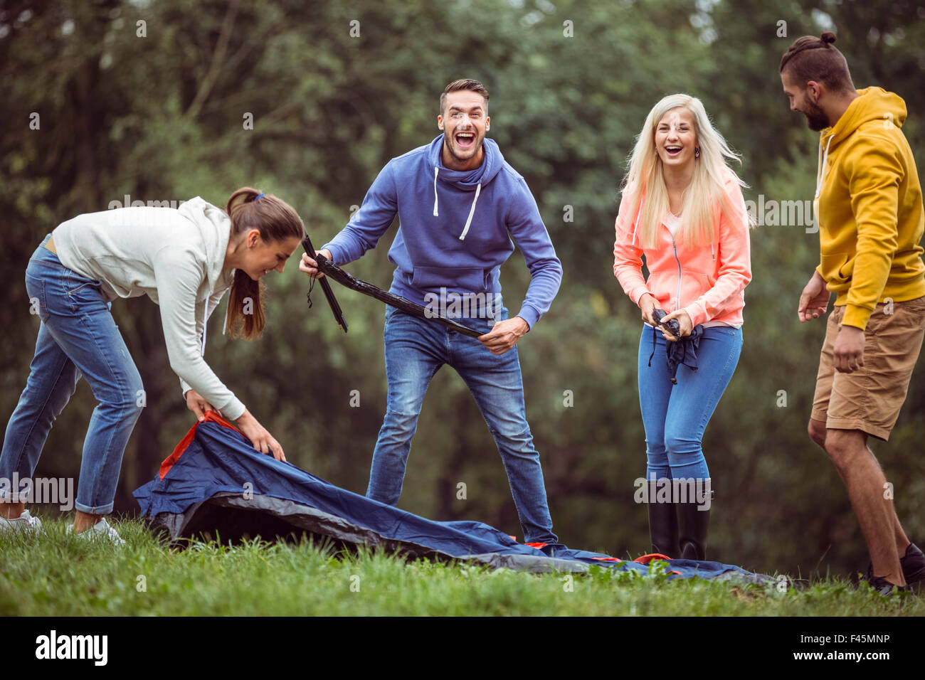 Happy friends setting up their tent Stock Photo