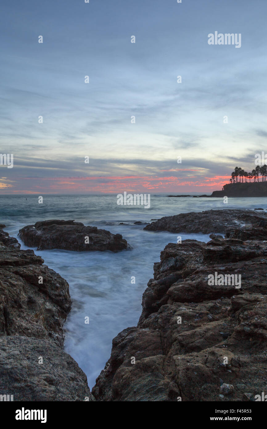Sunset over the rocks at Shaws Cove in Laguna Beach as water flows over the stone Stock Photo