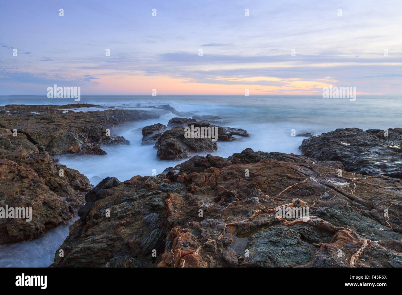 Sunset over the rocks at Shaws Cove in Laguna Beach as water flows over the stone Stock Photo