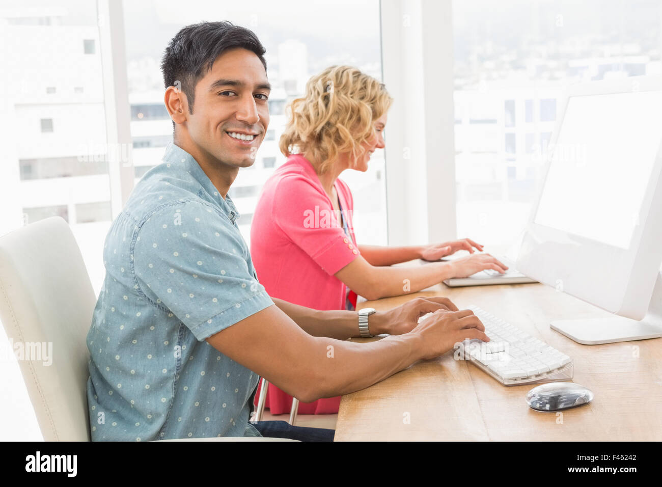 Portrait of smiling man working in front of his colleague Stock Photo