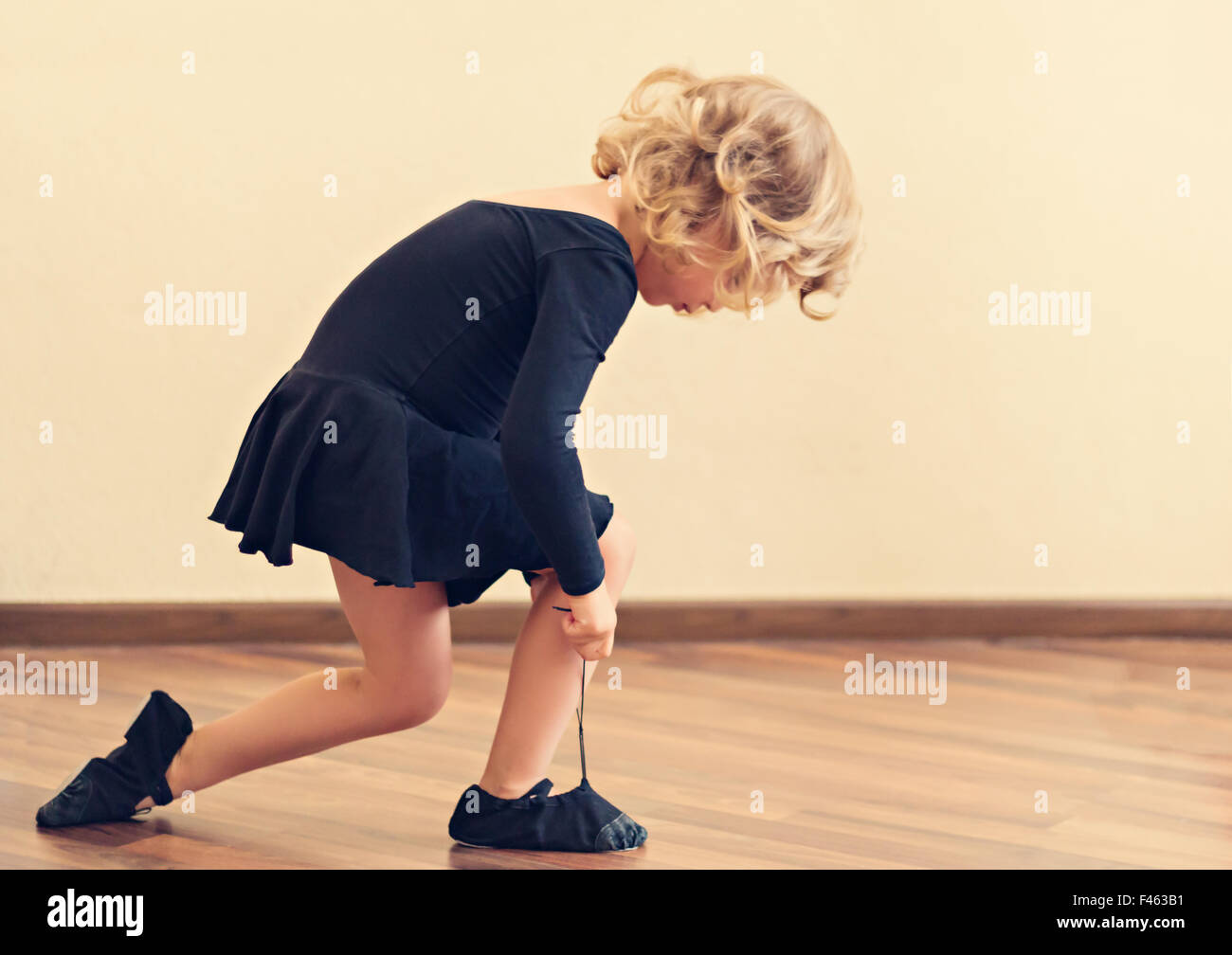 Funny little girl put on shoes for dance. Selective focus. Stock Photo
